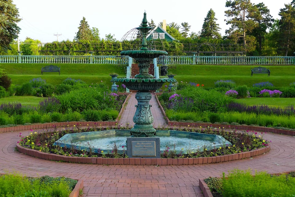 A classical fountain with a plaque in a landscaped garden.