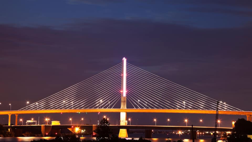 A large cable-stayed bridge at night with illuminated cables and a central tower.