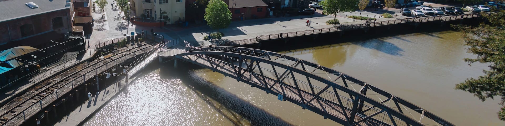 A river with a bridge, buildings, and a train track.