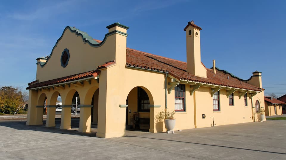 A historic building with a red-tiled roof, arched doorways, and a prominent tower.