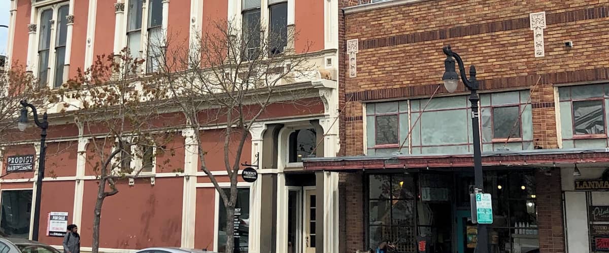 A historic building with a Coca-Cola mural, parked cars, and storefronts.