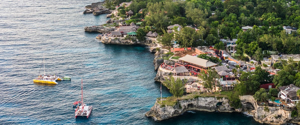Negril, Jamaica, aerial landscape view of area around the famous Rick's Cafe in Negril, with boats near the cliff jumping spot and many people at the cliff