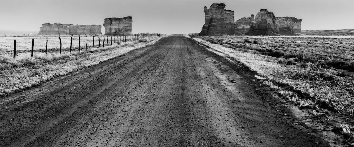 A dirt road leading to ancient stone ruins in a barren landscape.