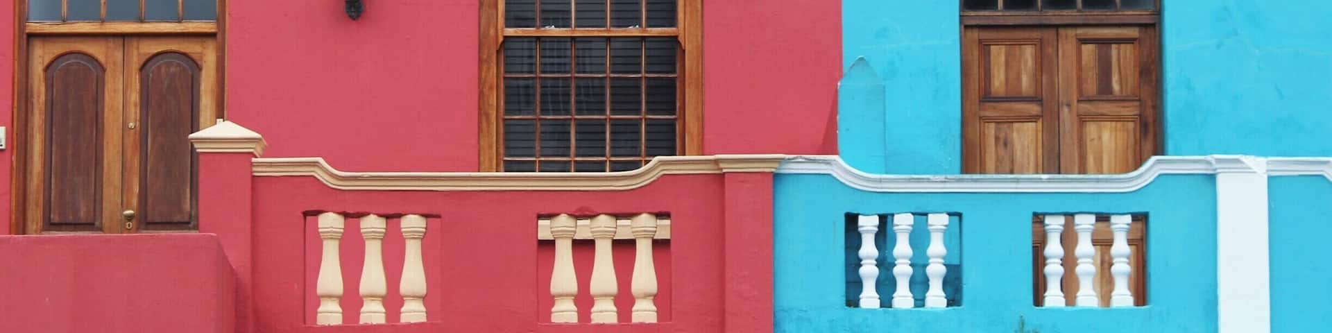A building with two distinct facades, one red and one blue, featuring wooden doors and windows.