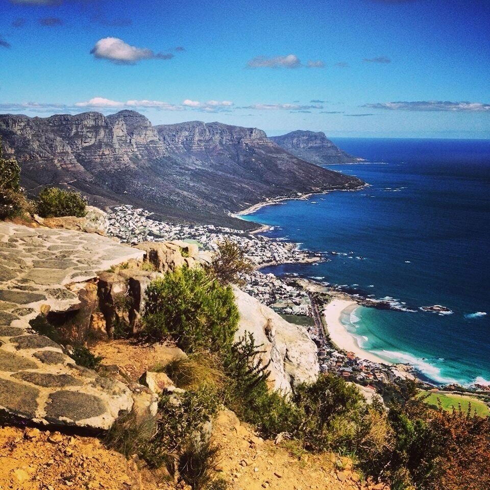 A coastal landscape with a rocky cliff, a beach, and a town by the sea.