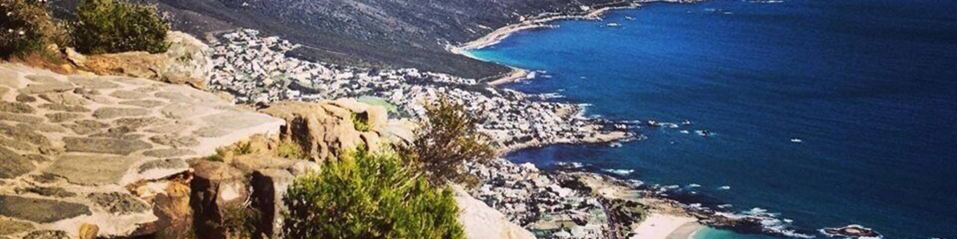 A coastal landscape with a rocky cliff, a beach, and a town by the sea.