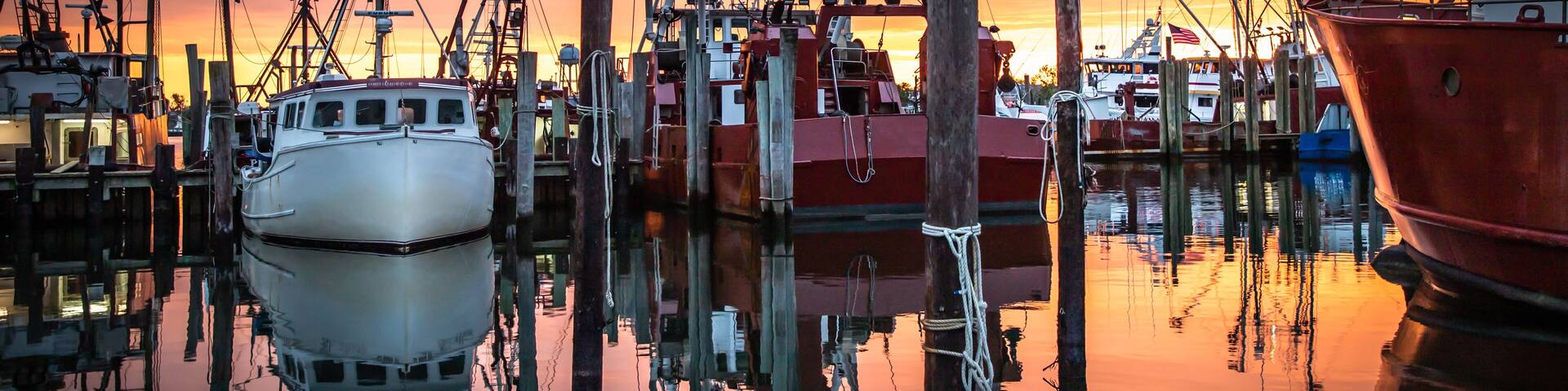 Un puerto deportivo con barcos amarrados a muelles de madera al atardecer.
