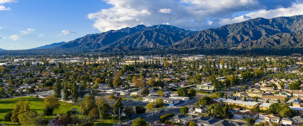 A residential area with houses, a park, and a mountain range in the background.