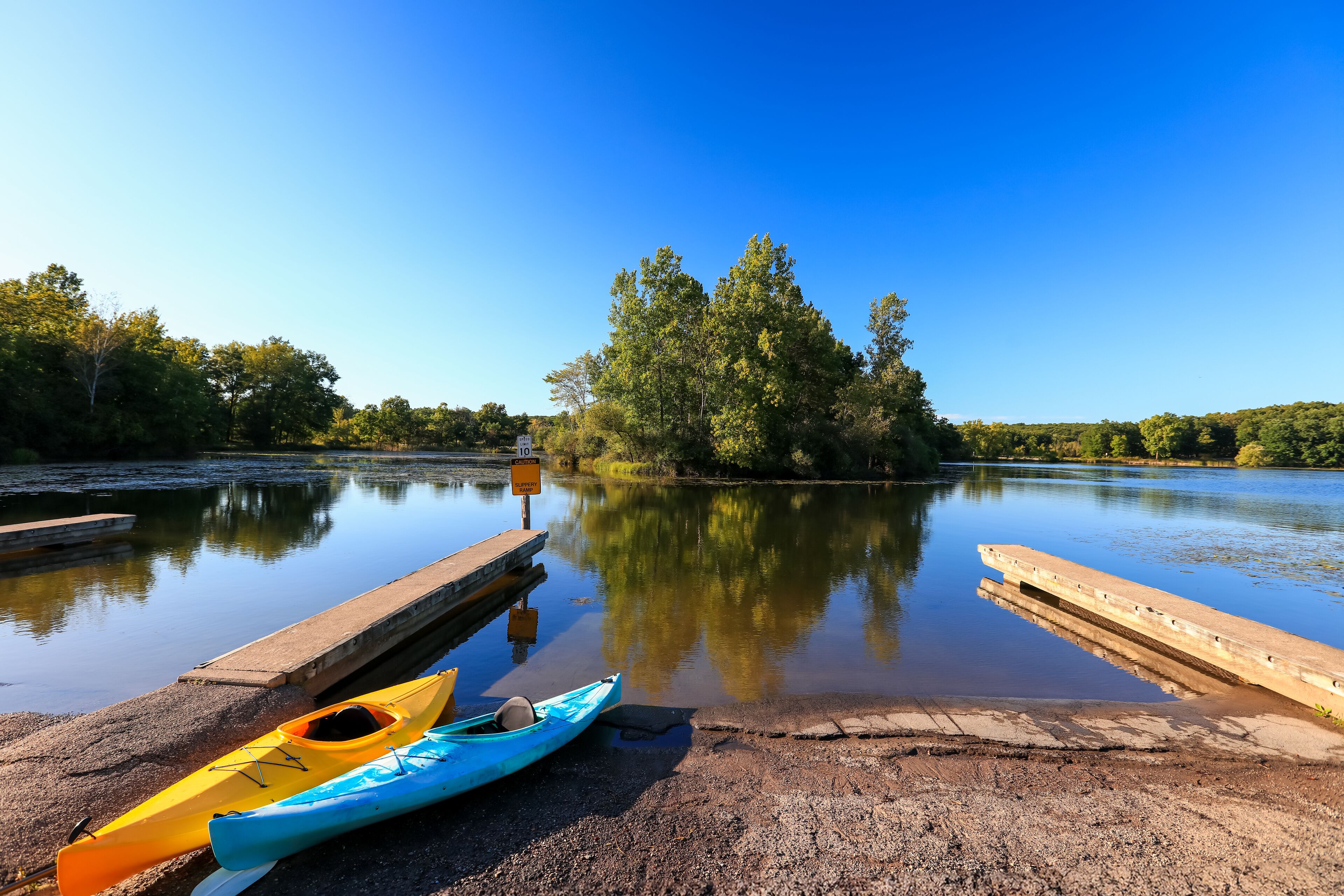 Kent lake in Kensington metro park with boat access and two kayaks at the shore.