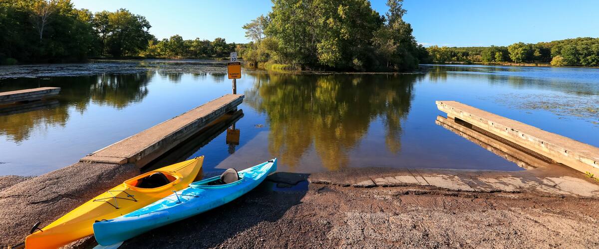 Kent lake in Kensington metro park with boat access and two kayaks at the shore.
