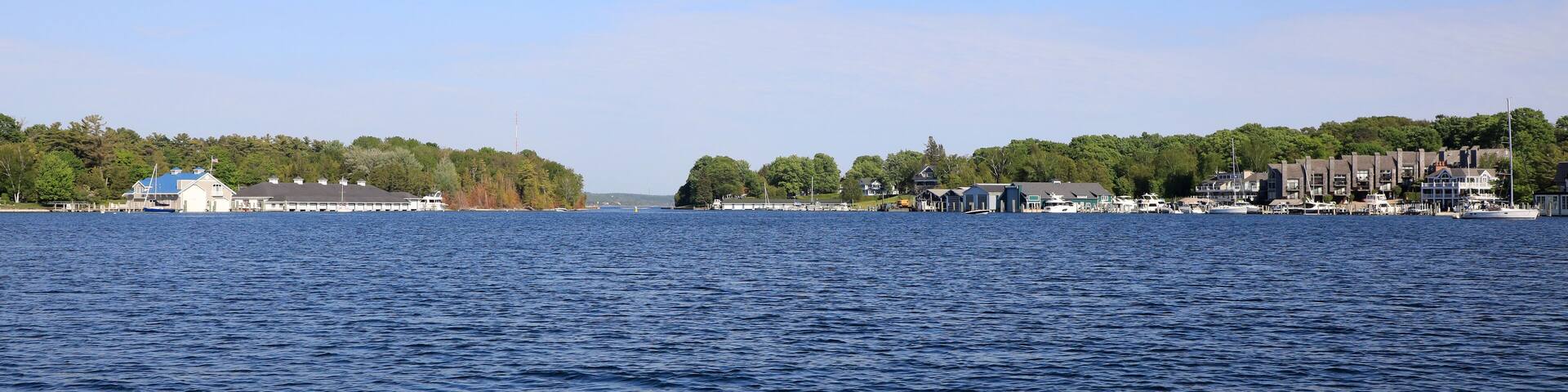 A calm lake with a dock and buildings on the shore.