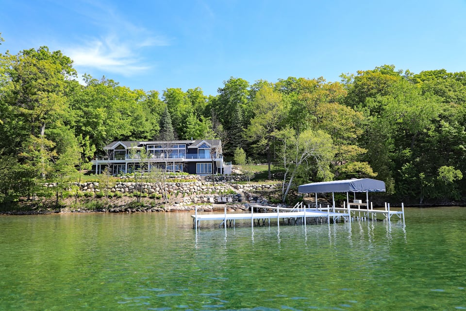 Une maison au bord du lac, avec un quai et une zone abritée.