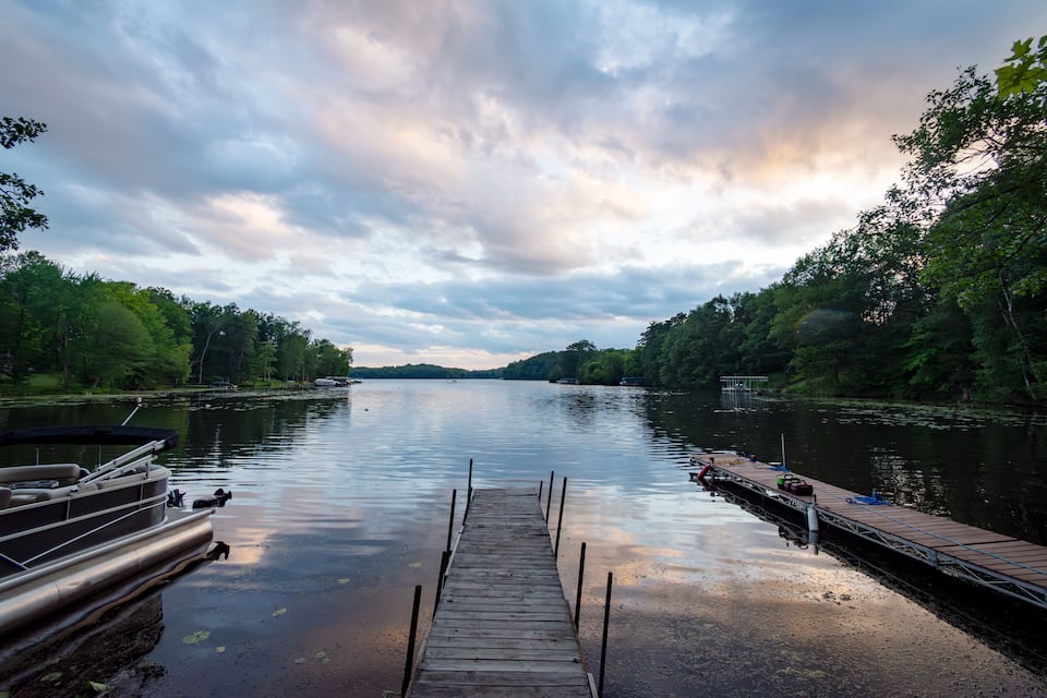 Une jetée en bois s’étendant sur un lac paisible, entouré d’une forêt dense.