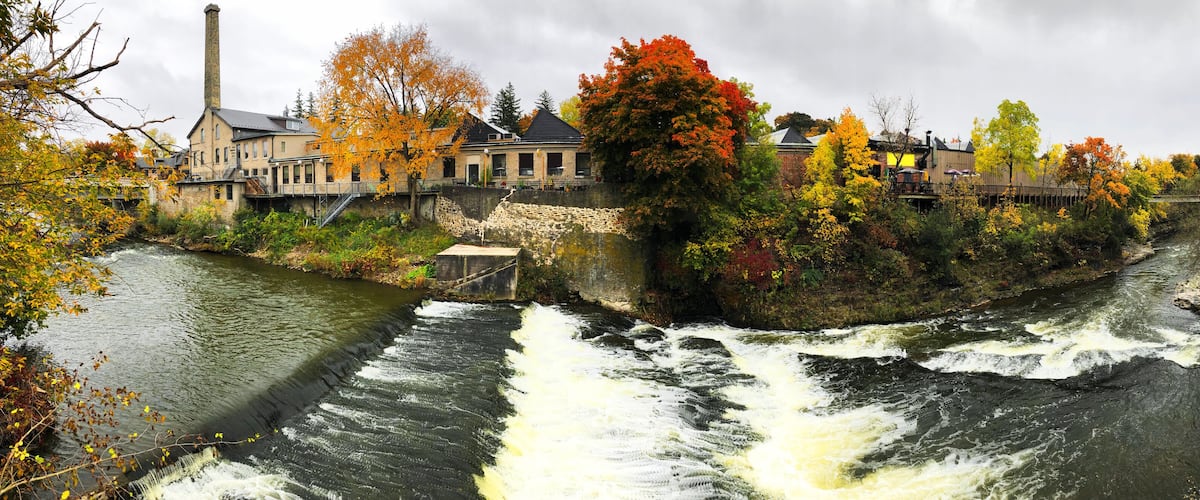 A river flowing through a town with autumn-colored trees and historic buildings.
