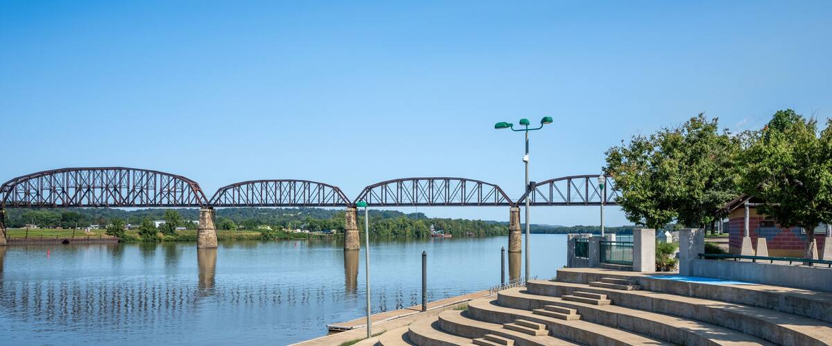 A river with a bridge, concrete steps, and a lamp post.
