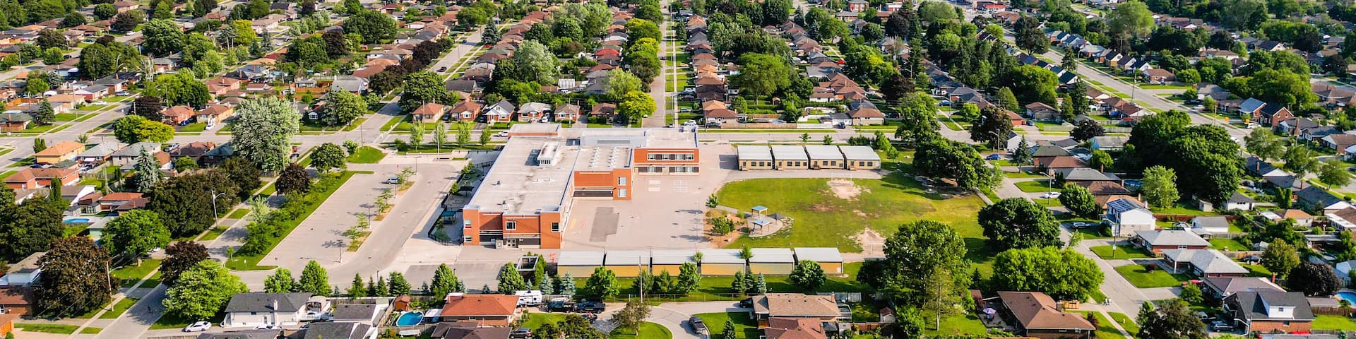 A suburban neighborhood with houses, green spaces, and a central building complex.