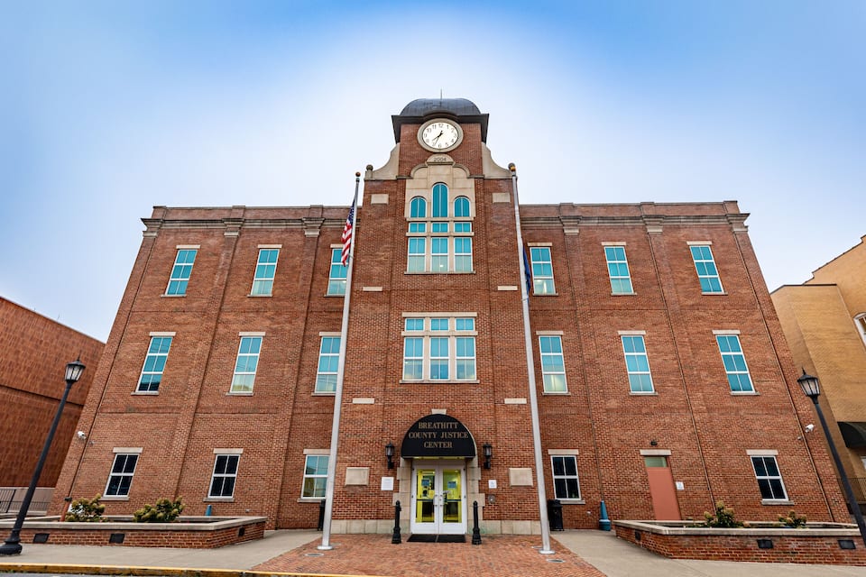 A brick courthouse with a clock tower, a flagpole, and a sign reading "Breathitt County Justice Center".
