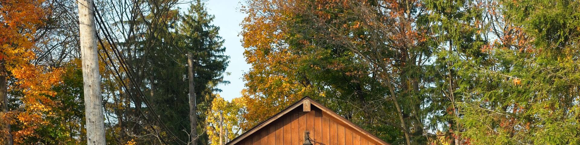 A wooden covered bridge in a wooded area with autumn foliage.