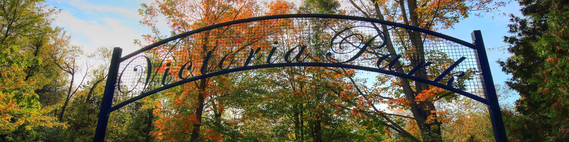 Un arco con la inscripción "Woods" en un parque con follaje otoñal.