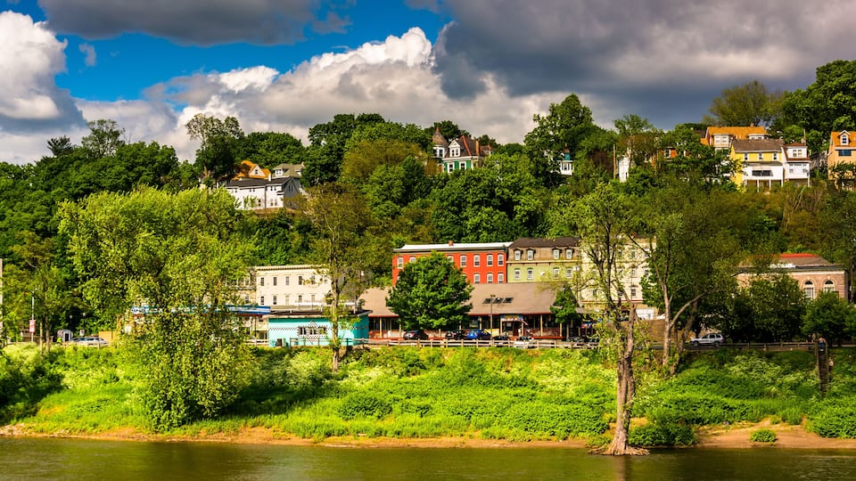 A riverside town with colorful houses, lush greenery, and a clear sky.