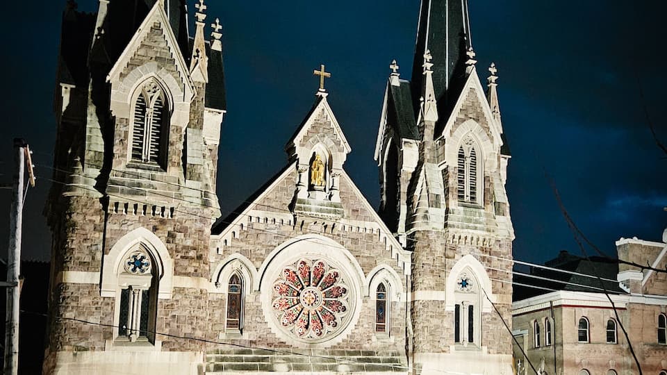 A Gothic-style church with two tall spires, a large rose window, and a clock tower.