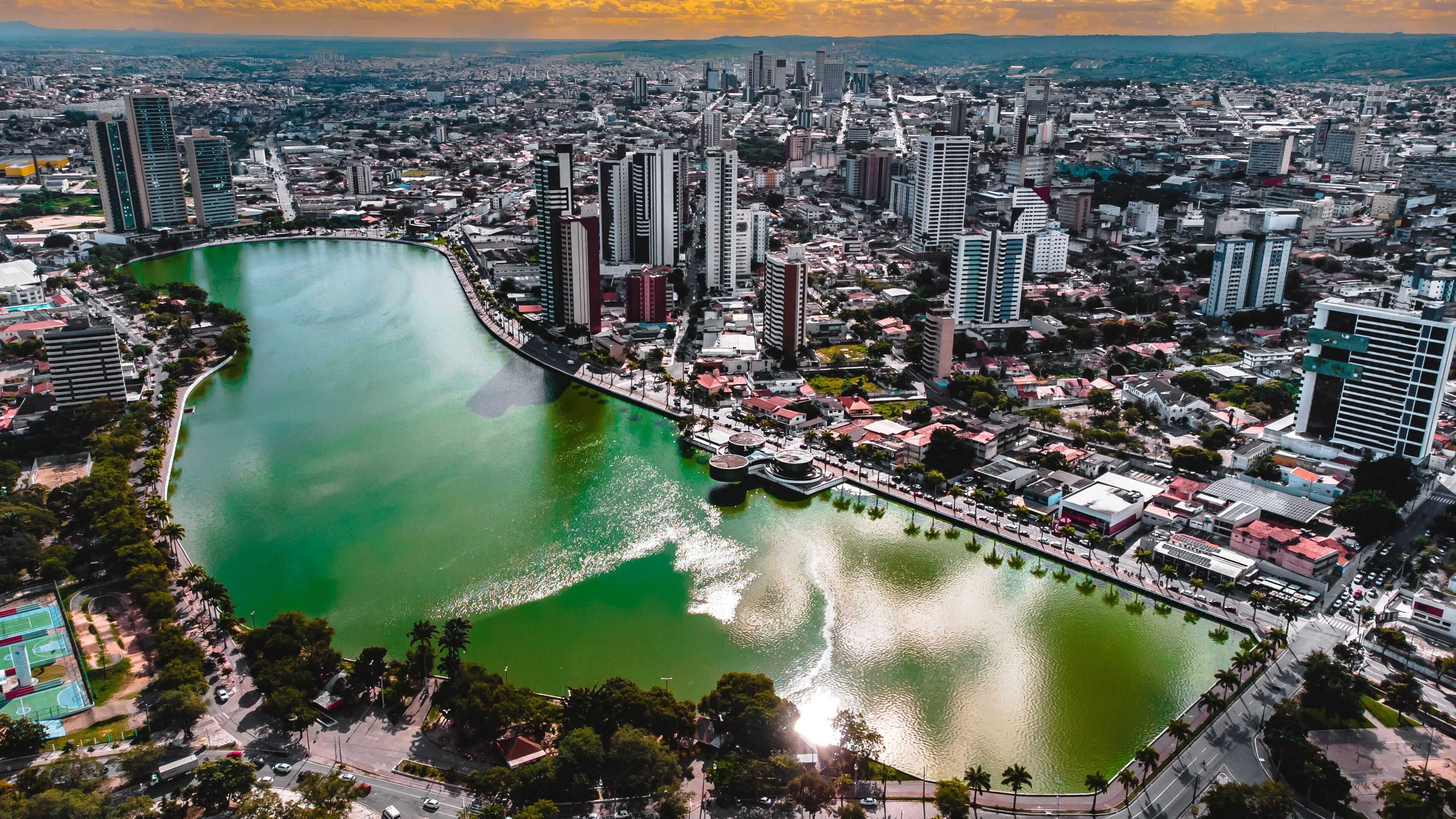 Paisagem urbana com um rio proeminente serpenteando por entre edifícios altos e uma mistura de construções residenciais e comerciais.