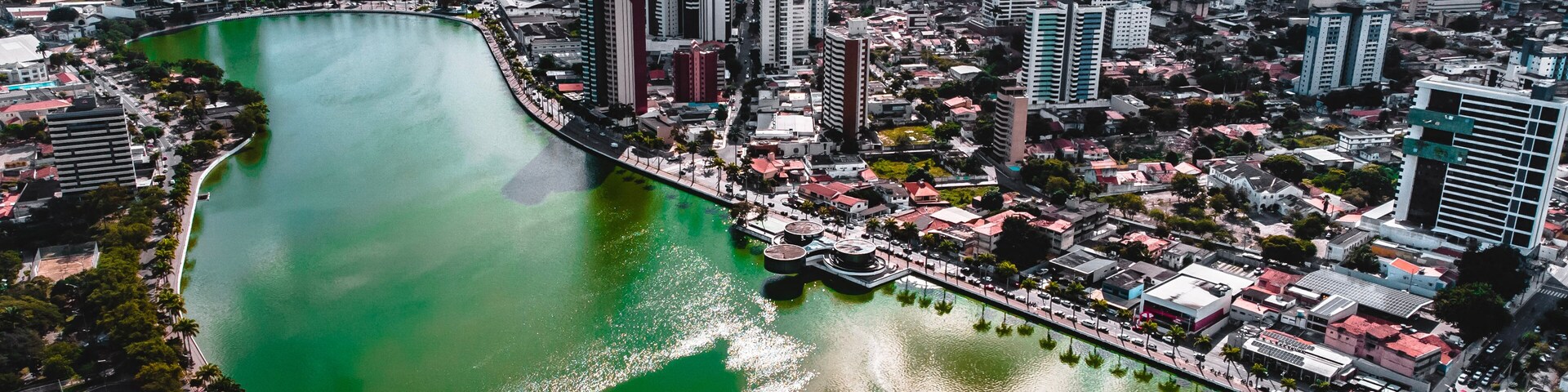 Paisagem urbana com um rio proeminente serpenteando por entre edifícios altos e uma mistura de construções residenciais e comerciais.