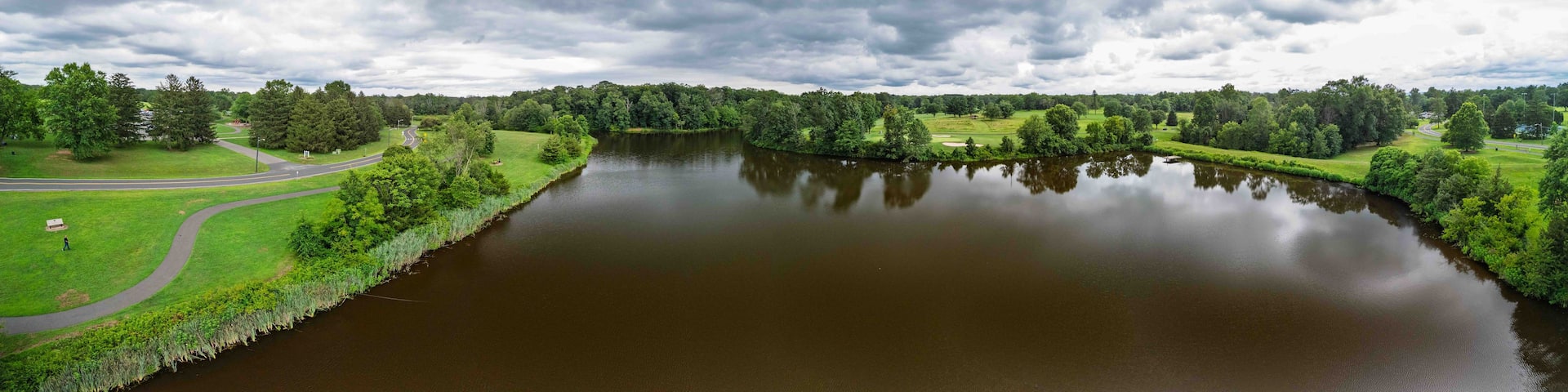A river winding through a park with a road and trees.