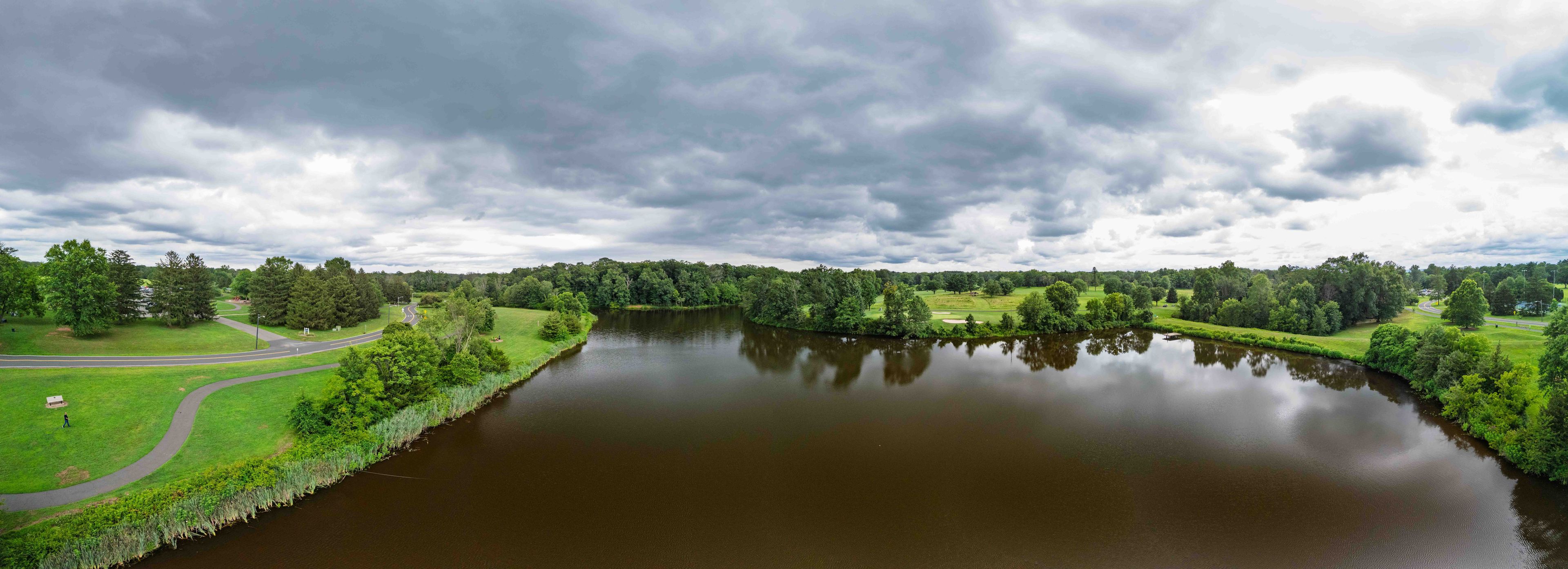 A river winding through a park with a road and trees.