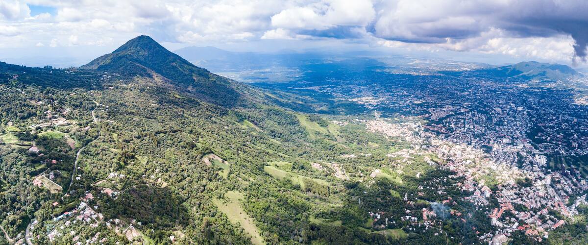 A mountainous landscape with a city in the foreground and a range of hills in the background.