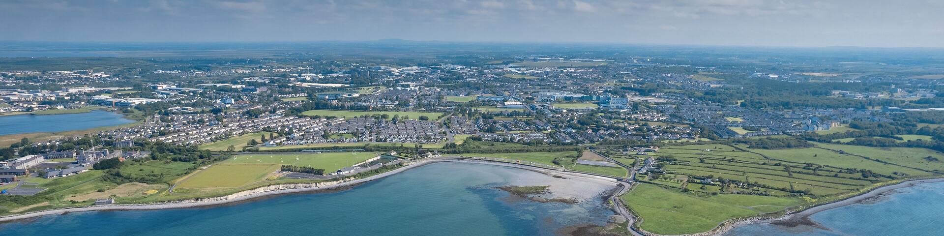Aerial view on Ballyloughane Strand in Galway city, Ireland. High tide. Blue cloudy sky and ocean water. Popular area with amazing view and footpaths for walk close to Renmore residential area