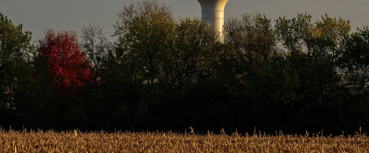 A water tower labeled "Plainfield" in a field with autumn-colored trees.