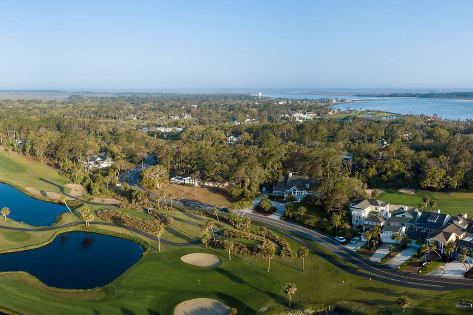 A coastal golf course with water hazards, a beach, and residential areas.