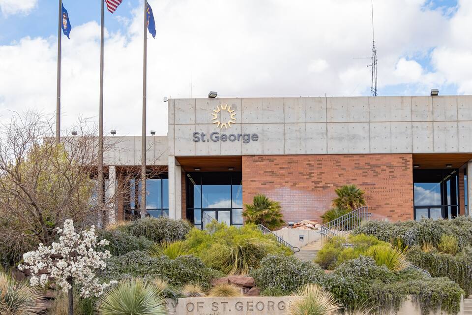 The St. George City Hall with the Utah state flag, a blue flag, and the American flag.