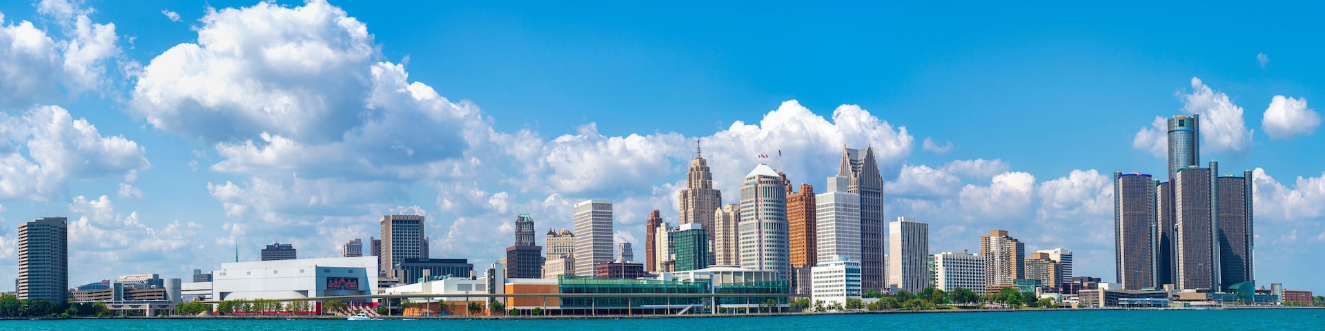 A city skyline with tall buildings and a body of water in the foreground.
