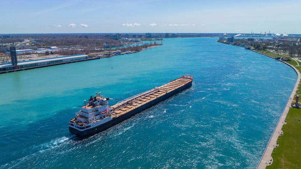 Bulk carrier sailed on St. Clair River aerial view. This river divided Port Huron, Michigan, USA (right) and Point Edward, Ontario, Canada (left).