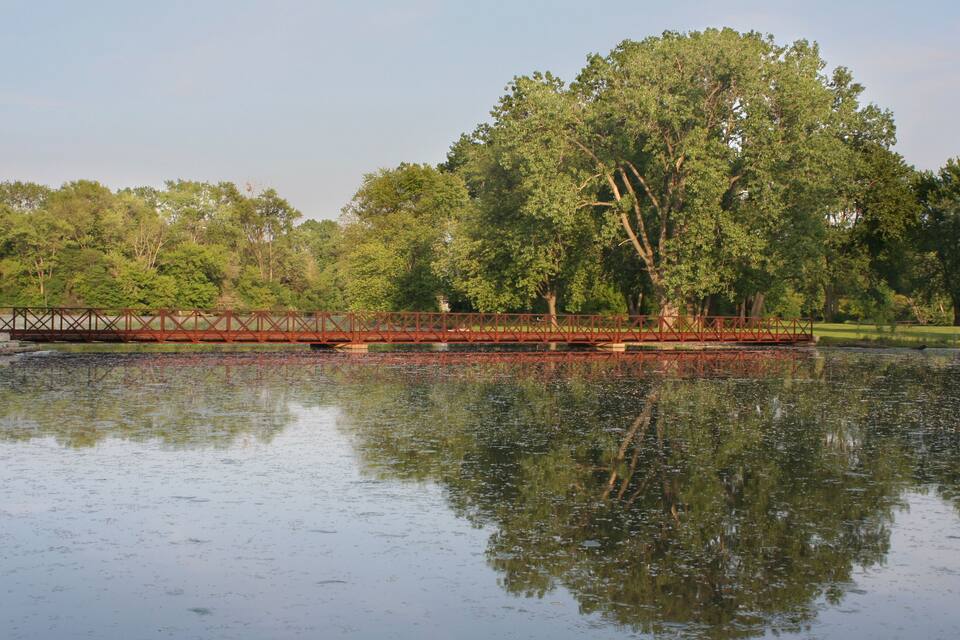 Un puente sobre un lago tranquilo rodeado de árboles.