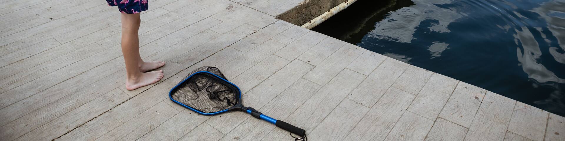 Boy reeling in small bluegill fish caught at lake