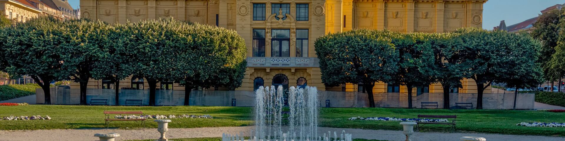 Zagreb, Croatia – July 18, 2025: The Art Pavilion in King Tomislav Square is illuminated by warm morning light, standing behind manicured lawns and red flower beds.