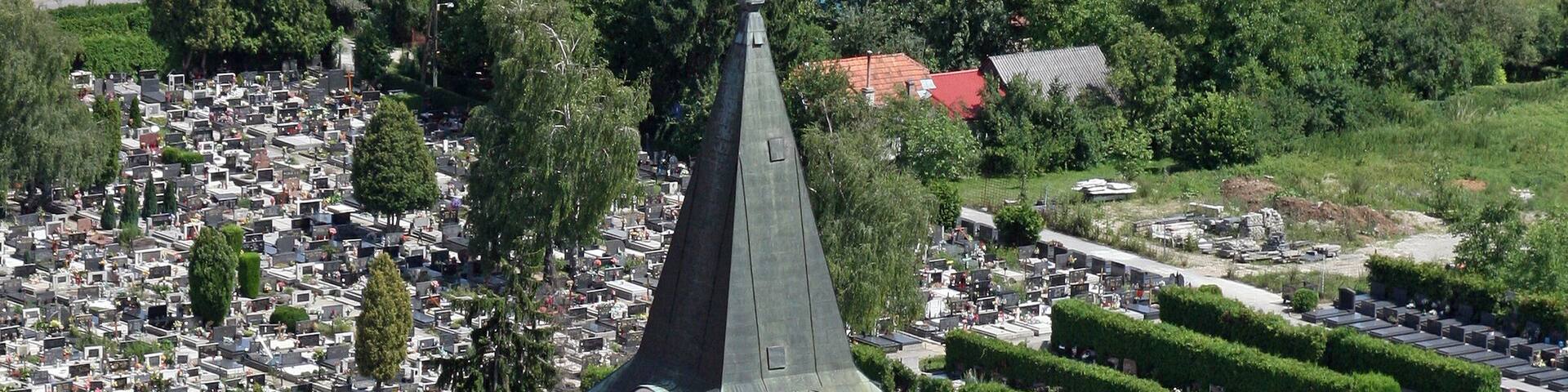 A church with a clock tower, surrounded by a cemetery and residential buildings.