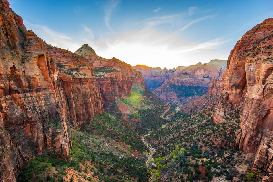 A canyon with steep red rock walls and a river running through it.