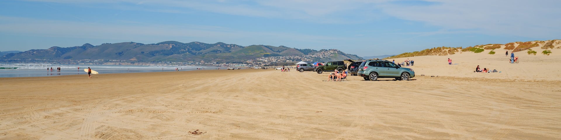 A sandy beach with vehicles and people.