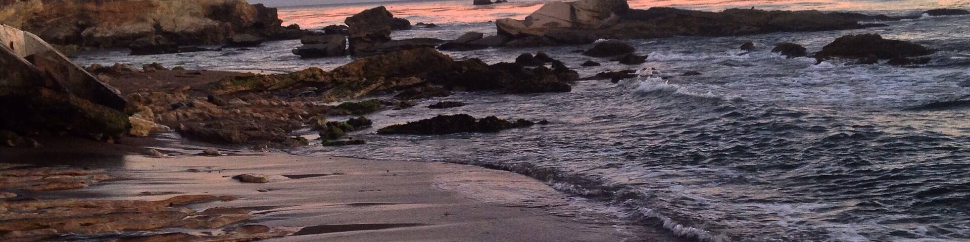 A rocky shoreline with waves at sunset.