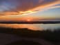 A sunset over a calm body of water with silhouettes of people and birds.