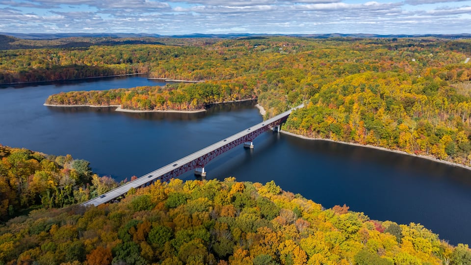 A river with a bridge, surrounded by autumn foliage.