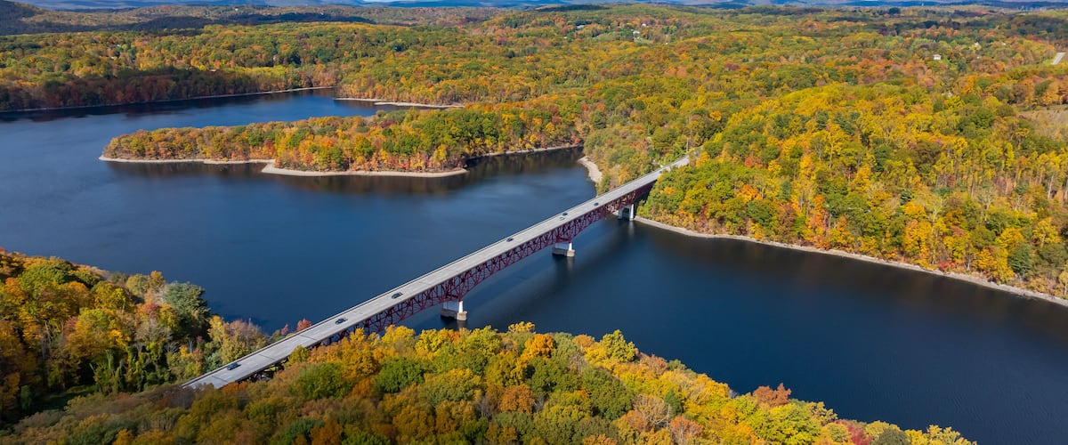 A river with a bridge, surrounded by autumn foliage.