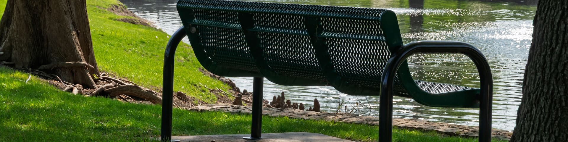 Empty park bench overlooking a calm pond and stone bridge