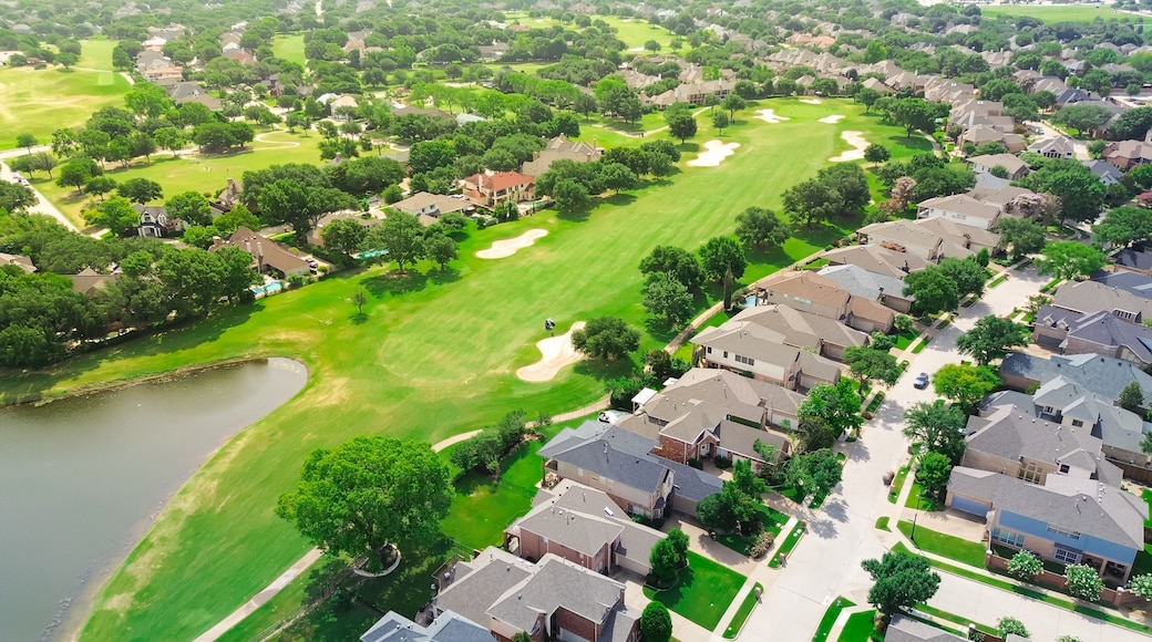Upscale golf community in master planned subdivision urban sprawl, grassy fairway, sand trap bunkers, golfer playing with expensive new development two story mansion houses, Plano Texas, aerial