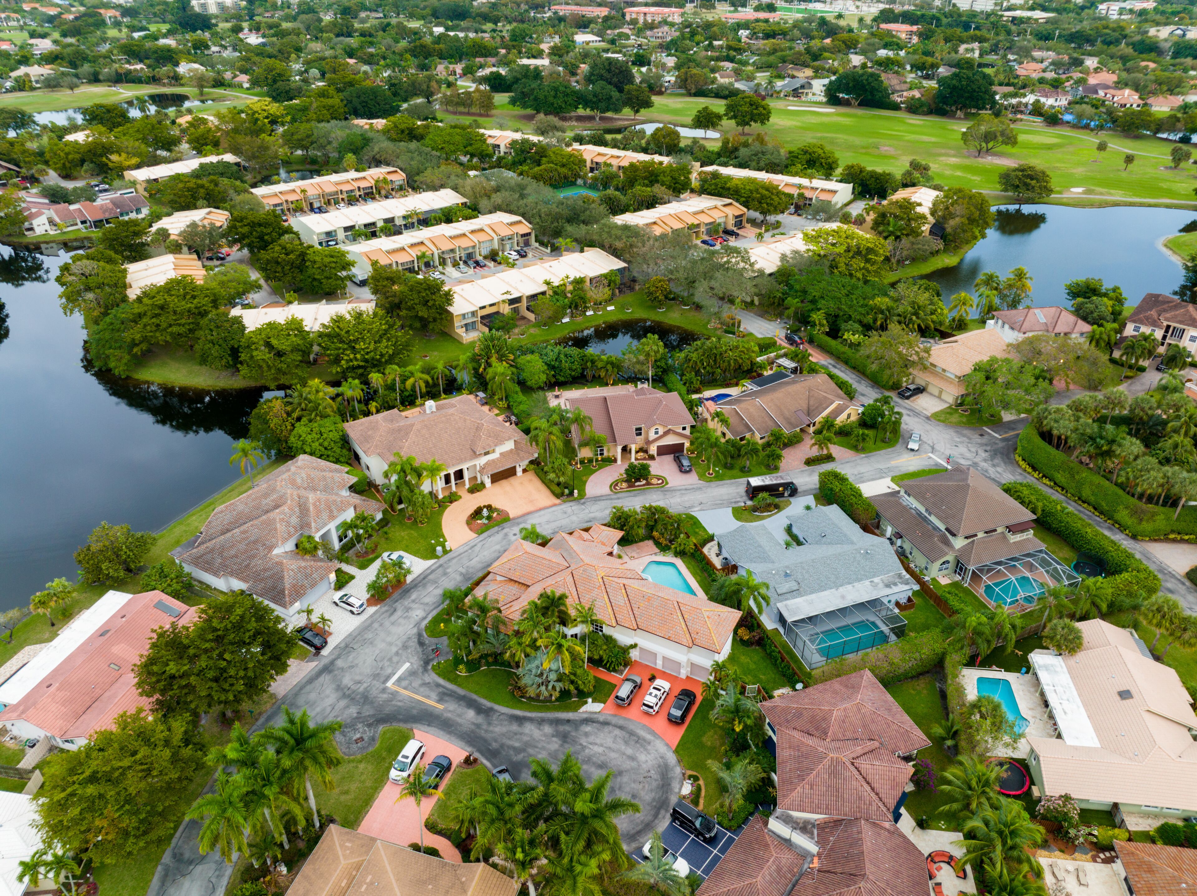 A residential area with houses, a golf course, and a body of water.