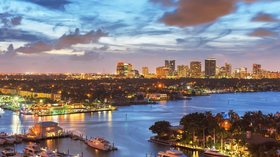 A marina with boats, a city skyline, and a waterfront.